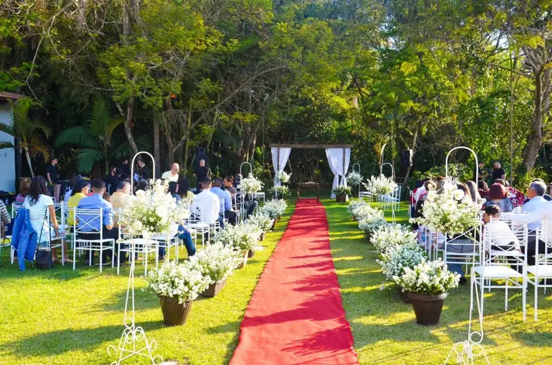 Cerimônia ao ar livre no gramado da chácara, com corredor vermelho e convidados sentados